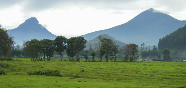 A stunning vista of the Virunga Mountains, featuring volcanic peaks and lush greenery across Uganda, Rwanda, and Congo